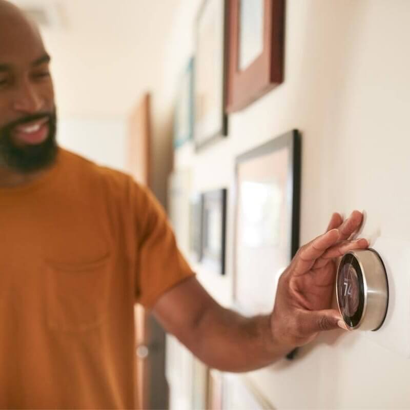 A man adjusting a smart thermostat.