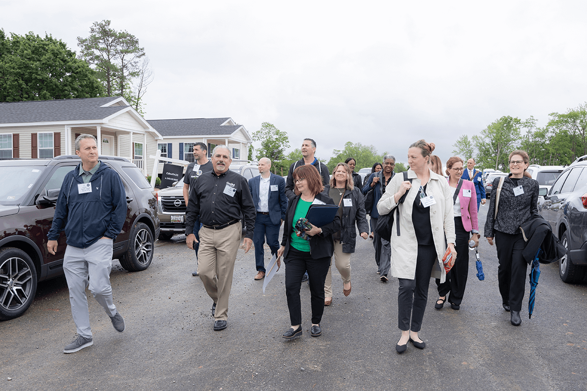 A group of people outside touring a housing development.